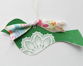 Green bird with white doily design and colorful floral ribbon