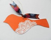 Orange bird with white doily design and colorful ribbon to hang