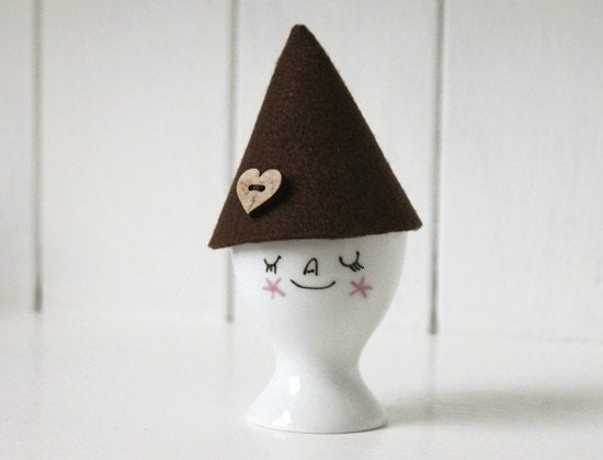 White smiley face porcelain egg cup with brown felt pixie hat cozy