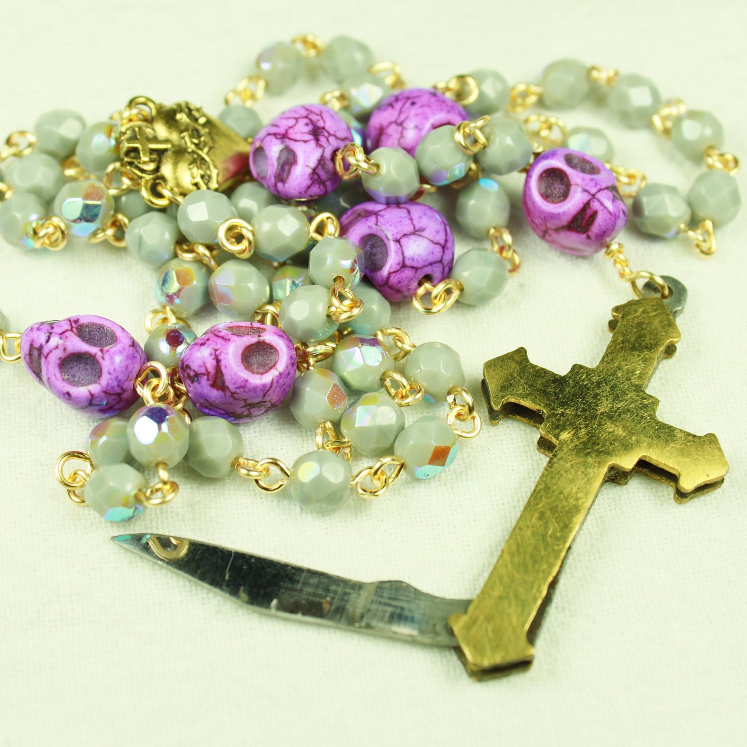 Muertos Skull Rosary in Gold with Knife Crucifix, Grey Iridescent Glass and Purple Stone Skulls