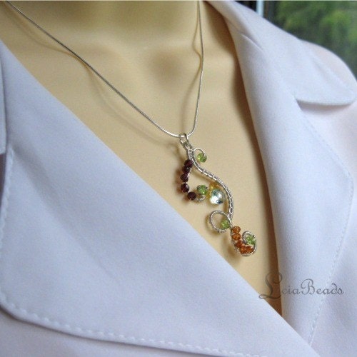 Intricate sterling silver wire wrapped pendant necklace with garnet, peridot, sapphire, and blue topaz