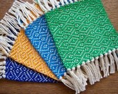 handwoven coaster set in BBQ blue, bright blue, yellow, and green, set of four