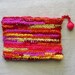 Zippered pouch crocheted in sunset stripes from colorful eco-friendly upcycled yarn, 7.5" by 5.5", red orange yellow pink coral