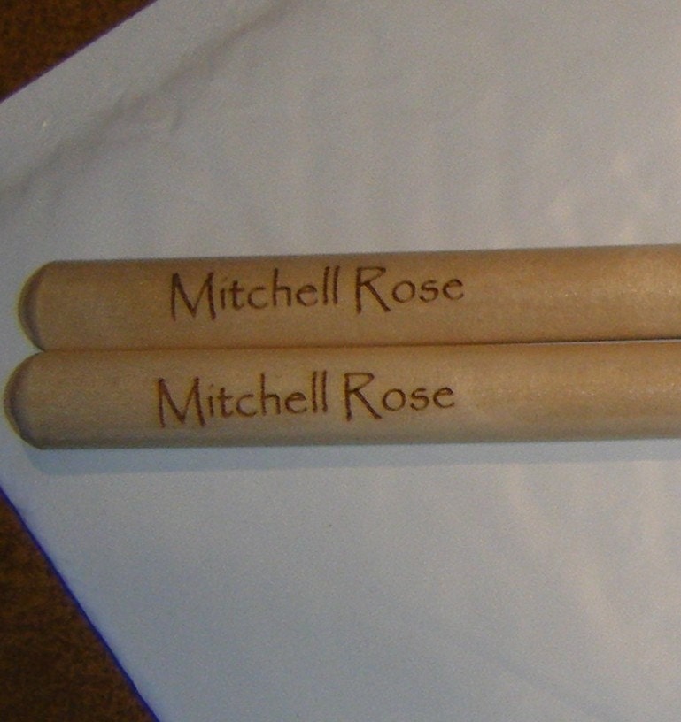 Personalized laser engraved drumsticks and a Display Rack for a single pair of sticks