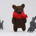 A brown bear with a red scarf, brooch