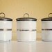 vintage enamelware canisters, 3 small tins with leather straps, white with gold striping from Germany