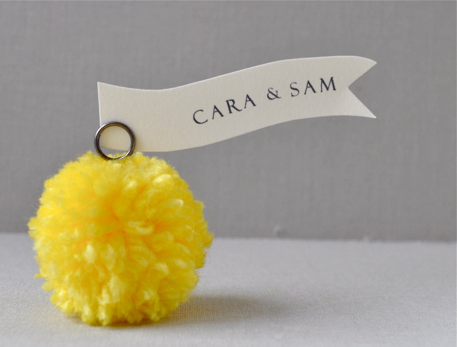 Sunshine/bright yellow yarn pom pom place holders, party decorations.  As sold online at Anthropologie May 2013