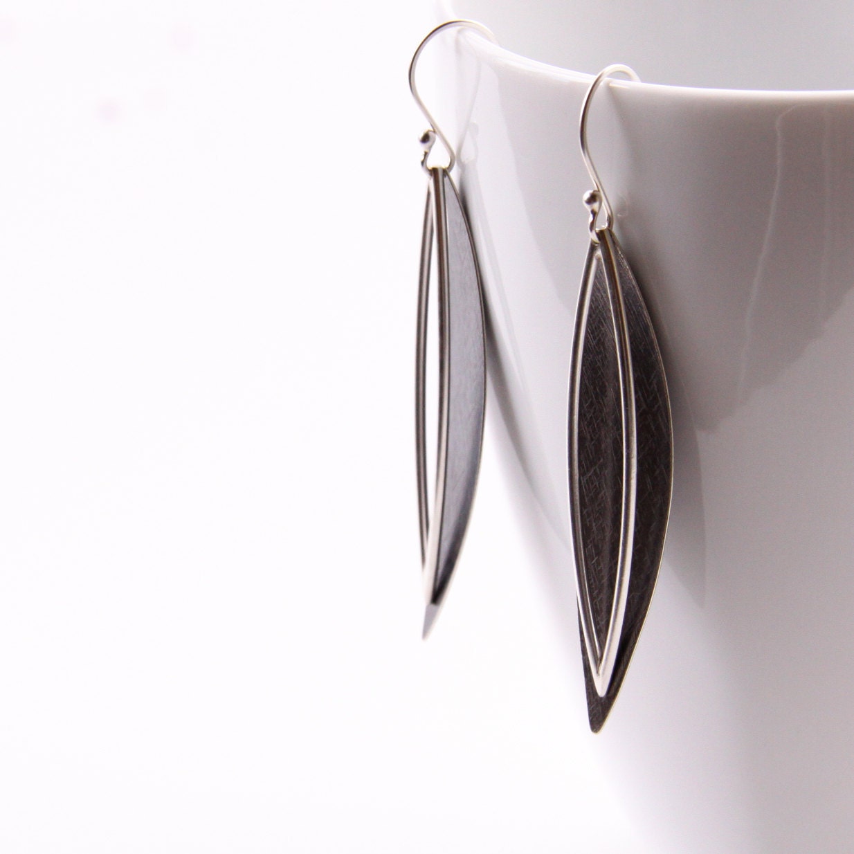 Long slender silver earrings constructed of similar shapes finished in different ways to contrast light and dark - "Spears Earrings"