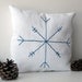 Small white cotton decorative pillow with blue embroidered snowflake