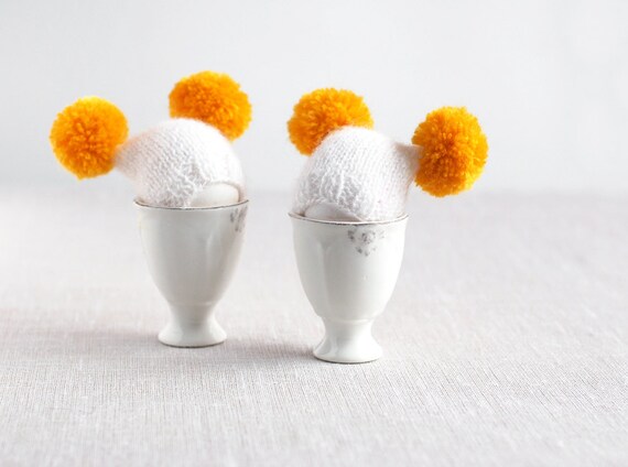 White egg warmers with funny yellow poms