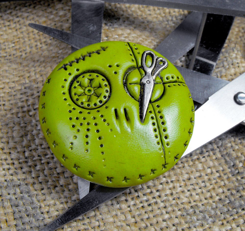 Happy lime green mini skull brooch with a pair of tiny scissors in his eye