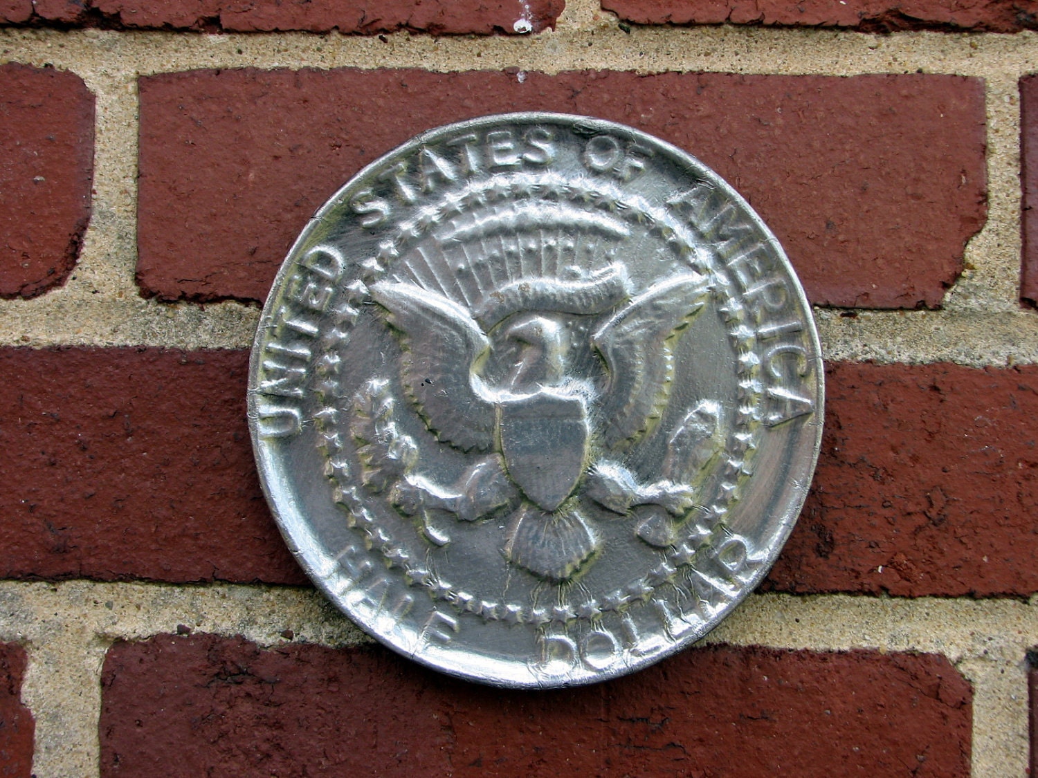 awesomely cool chalkware wall sculpture -- silver foiled half dollar replica
