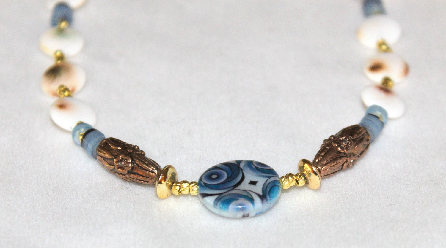 HOLDING for L's hubby - beaded necklace-decorative blue flat round shell- white brown Shiva eye disc- dark blue hammer shell Heische