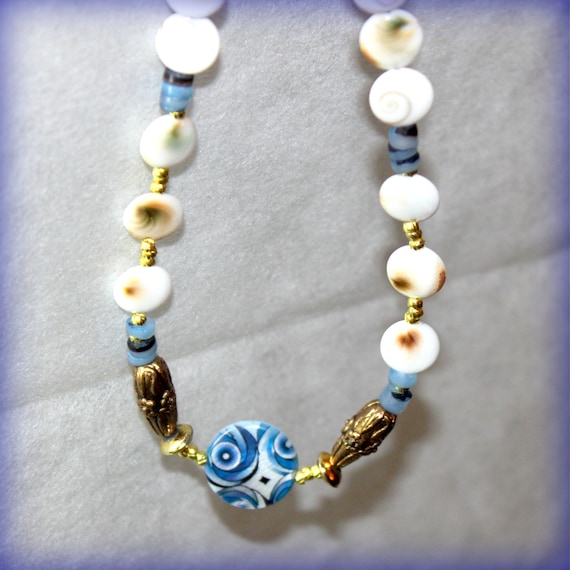 HOLDING for L's hubby - beaded necklace-decorative blue flat round shell- white brown Shiva eye disc- dark blue hammer shell Heische