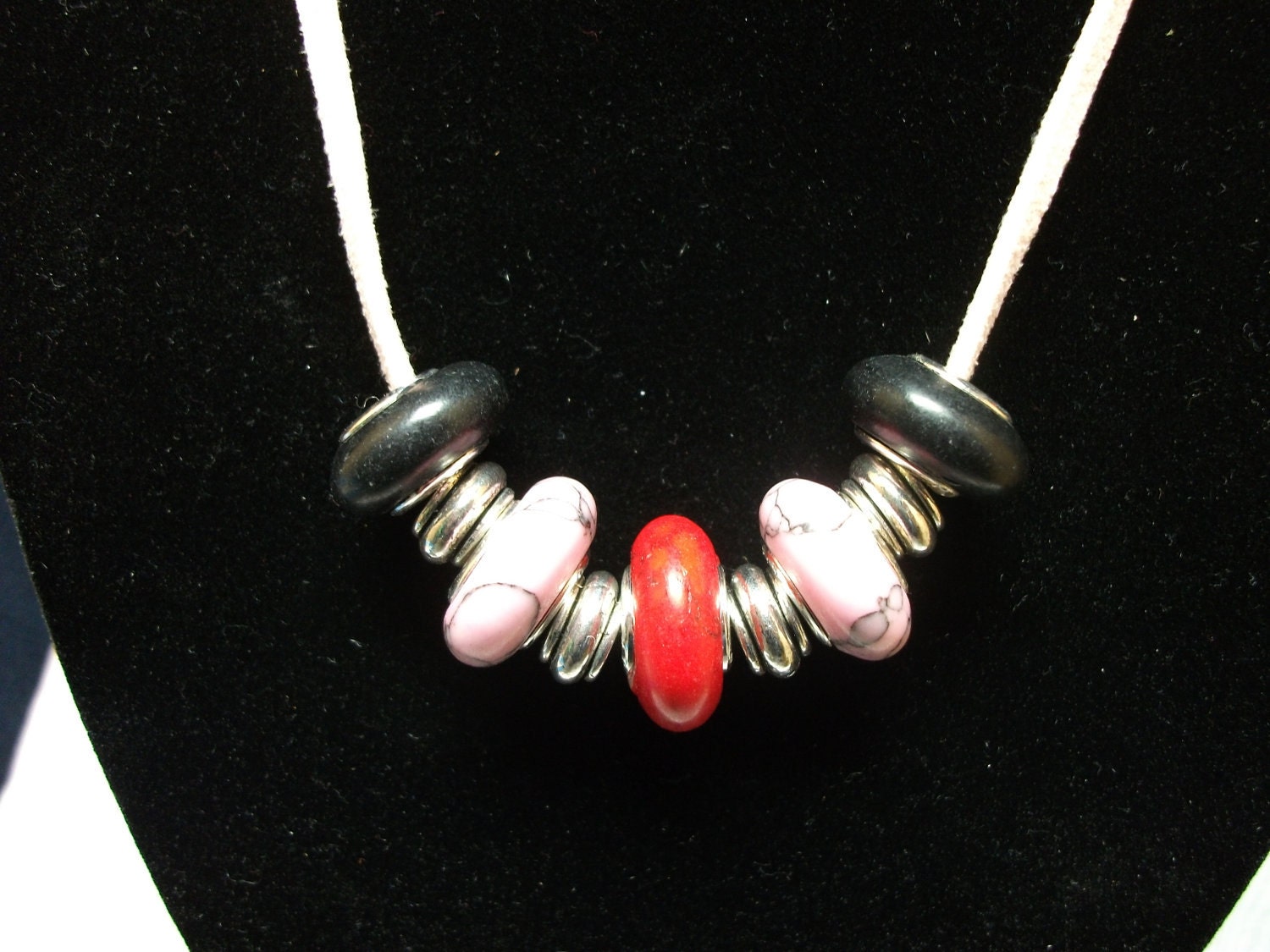 Turquoise necklace on pink suede with beads in pink black and red