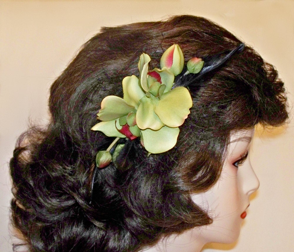 Hair fascinator of double green orchids, black french netting, and black feathers.