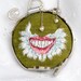 Green embroidered necklace of a mightily winged smile wrapped in typewriter keys "Pneumothorax"