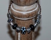 Foxes and flowers charm bracelet, brown leather strap, black glass beads, antique silver spacers