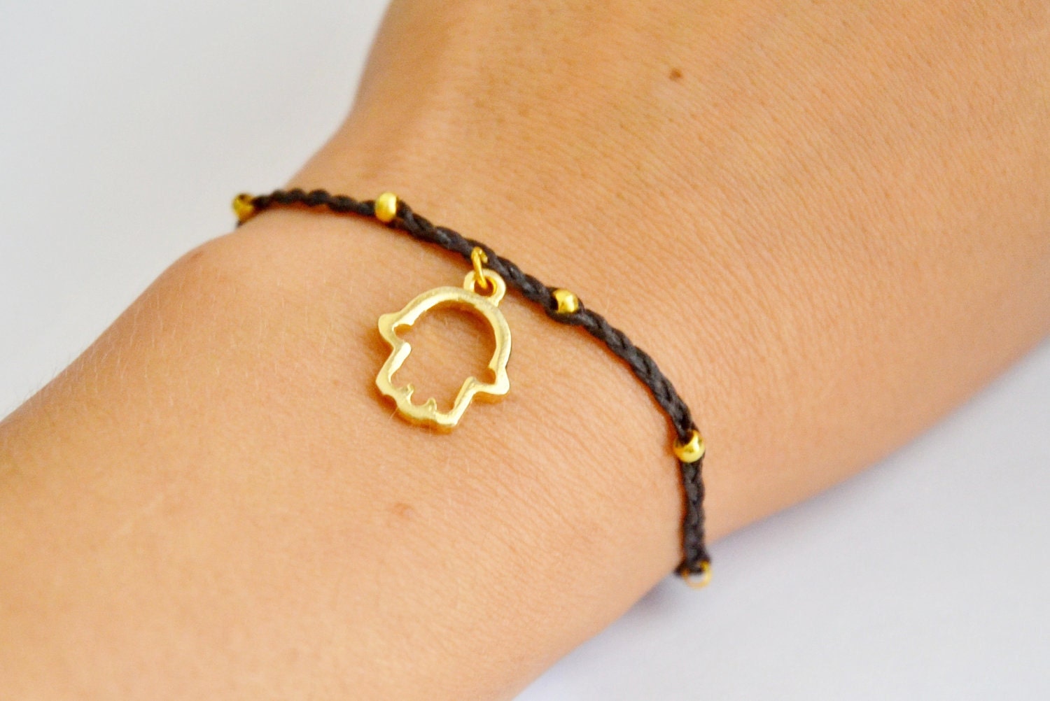 Braided Hamsa Bracelet  - braided bracelet with a gold plated hamsa charm and a braided black cord. Decoreated with gold plated beads.