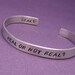 Hunger Games Inspired - Real Or Not Real - A Double Sided Hand Stamped Aluminum Bracelet