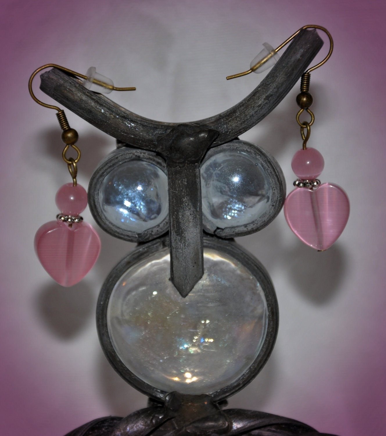 Glass heart shaped tiger eye heart, topped off with a small round pink tiger eye bead. The earrings are made using antique gold.