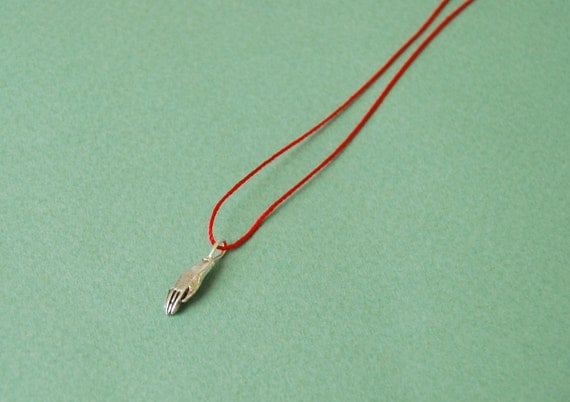 Silver hand on red silk cord