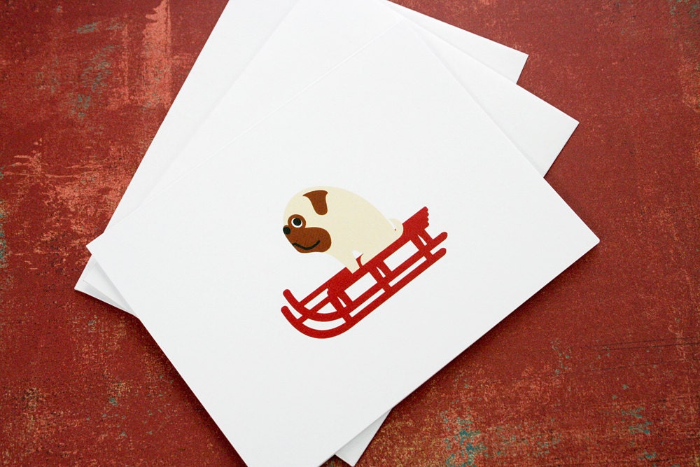 Christmas card, pug riding a red sled.