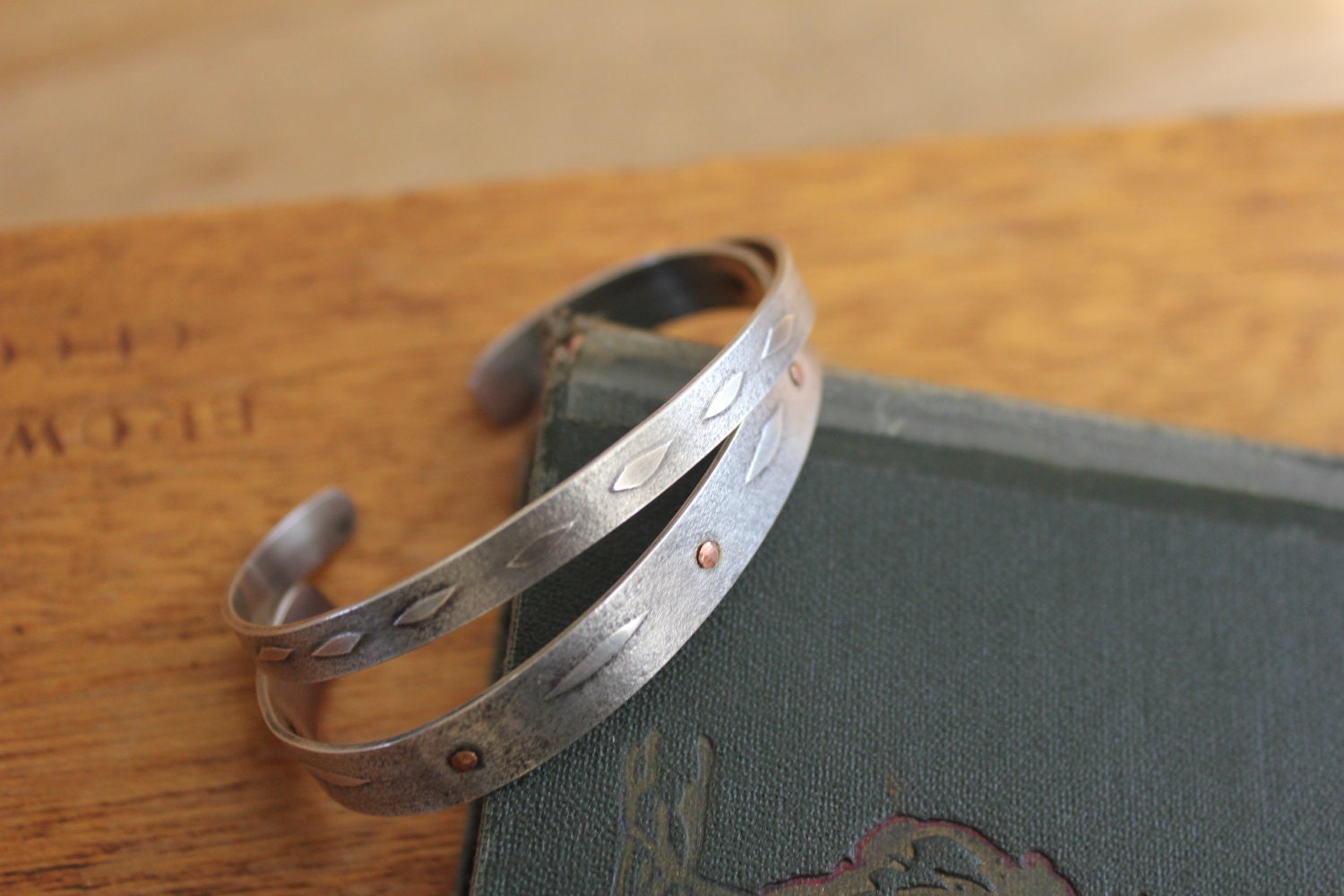 Set of two sterling cuff bracelets with embossed leaf texture and copper rivets