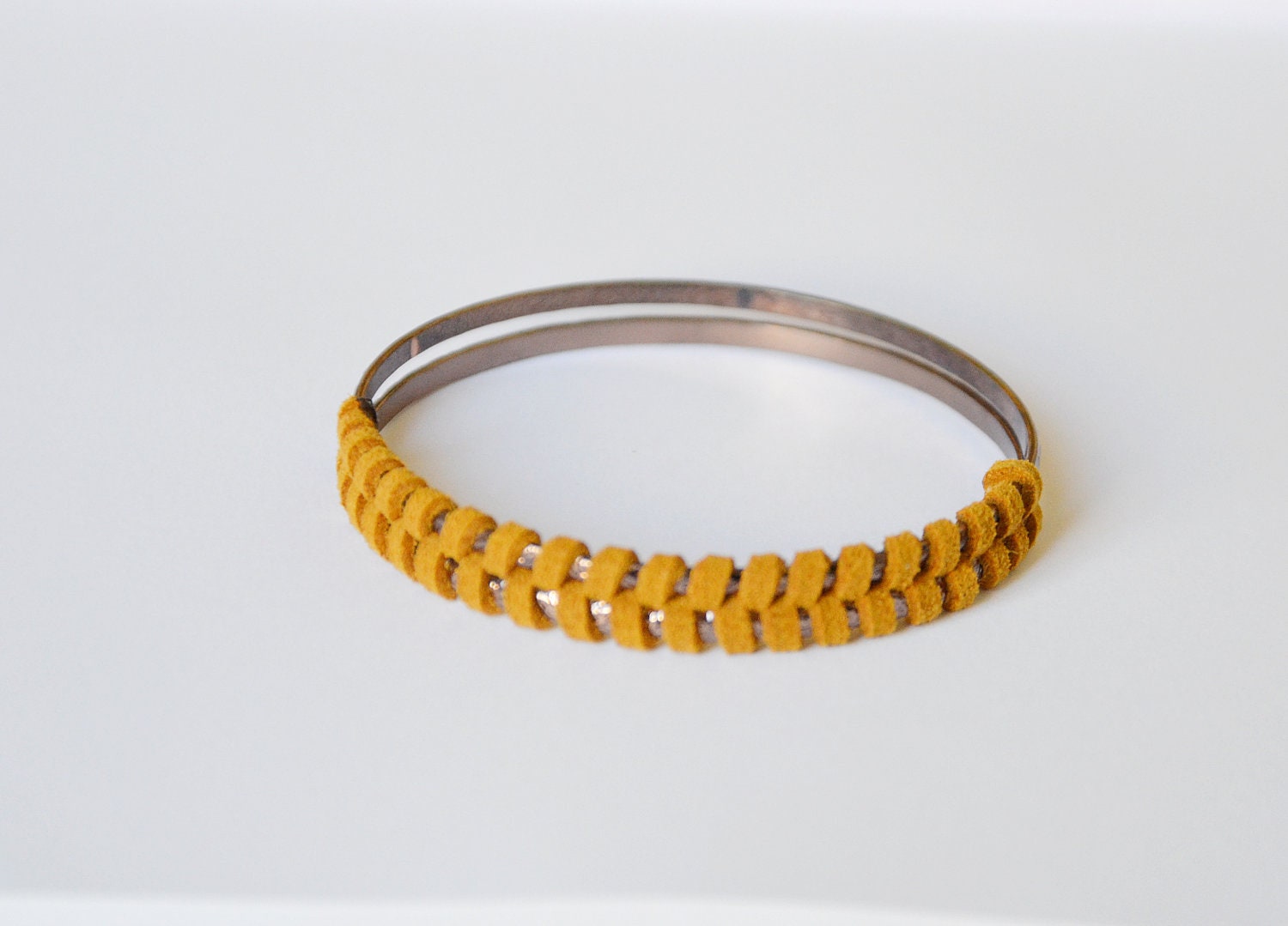 Suede bangle. Saddle brown suede, herringbone pattern woven together around two bronze colored bangles. Small size.