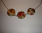Fabric Button necklace light green background with golden yellow, pink and purple flowers