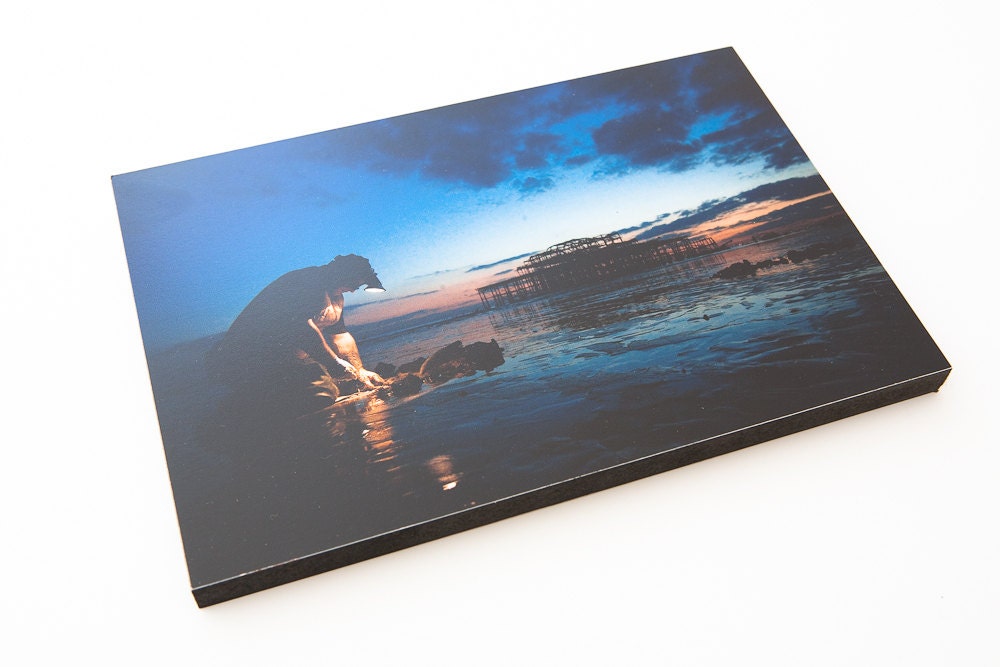 Digging for lug worms at dusk with Brighton's West Pier. 9" by 6"  Wooden block mounted Photograph.