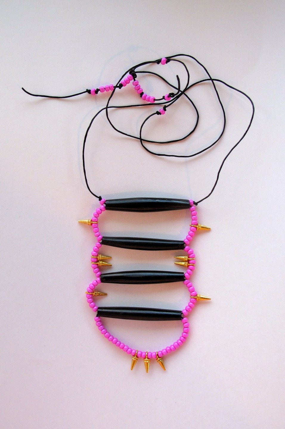 Tribal beaded necklace with hot pink beads and gold spikes with bone beads on black leather cord