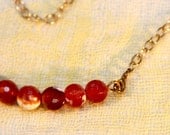 Bright orange coloured jade necklace. Variegated with white. Seven sphere arc with gold plated chain. Medium length