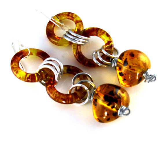 Amber earrings with aluminum hammered rings. Sterling silver ear wire.    Stylish, dangle , long. Modern earrings by Fashion Brand Faina.