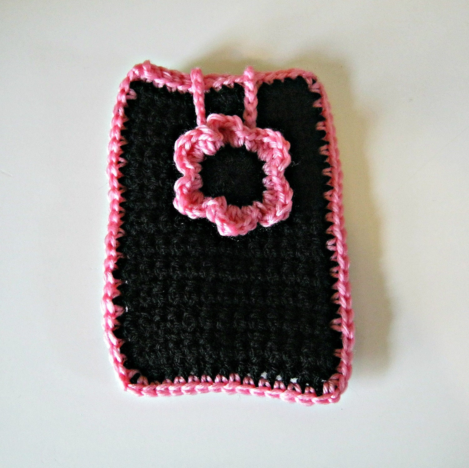 Crocheted phone cover in black with a pale pink flower and trim