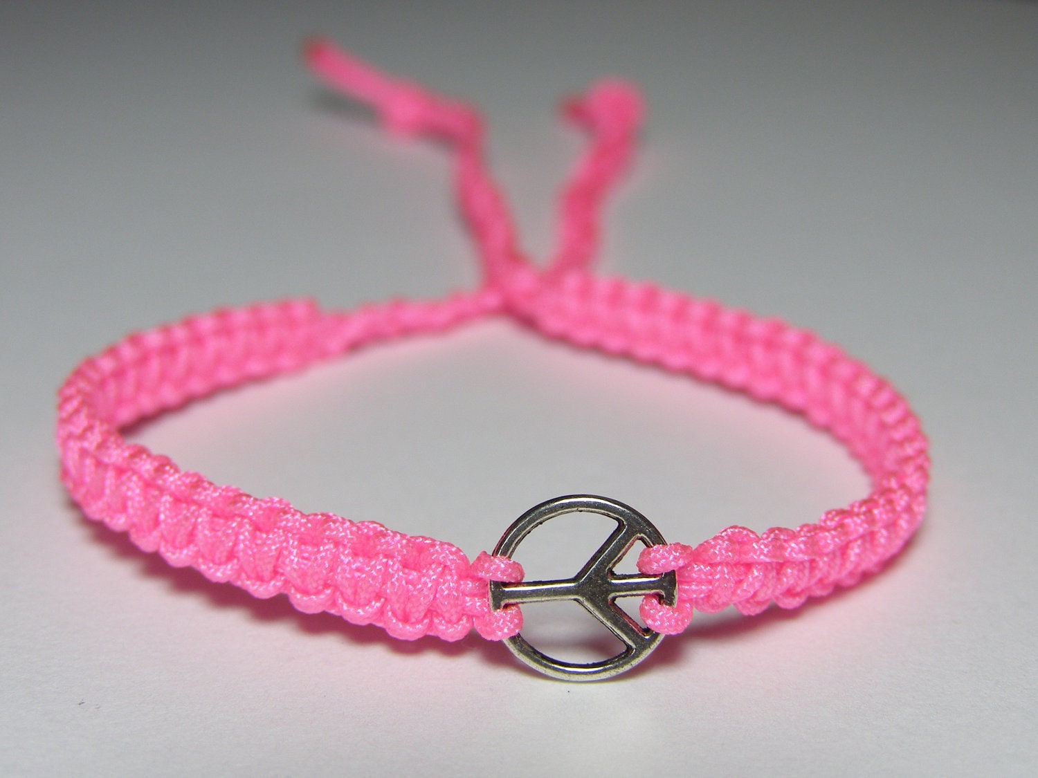 Bracelet with tiny peace sign and bright pink nylon thread