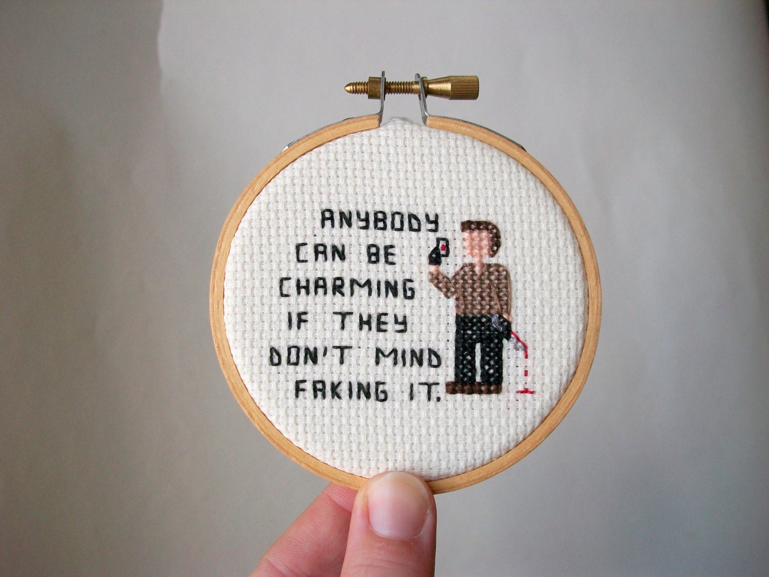 Pop culture serial killer cross stitch -- pixel person killer holding a bloody slide and knife, finished cross stitch