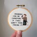 Pop culture serial killer cross stitch -- pixel person killer holding a bloody slide and knife, finished cross stitch