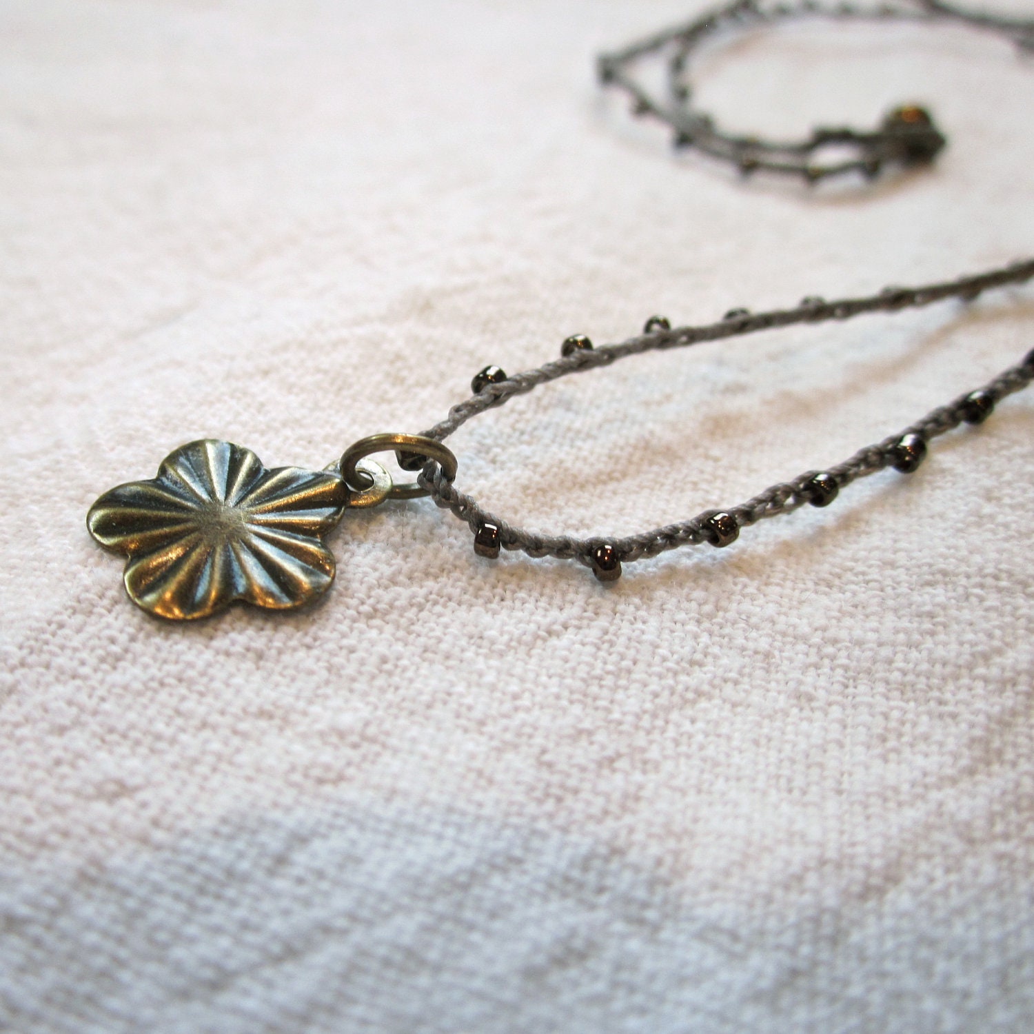 Tiny Bronze Flower Burst charm pendant on daintiest crocheted beaded necklace with brown and bronze strand