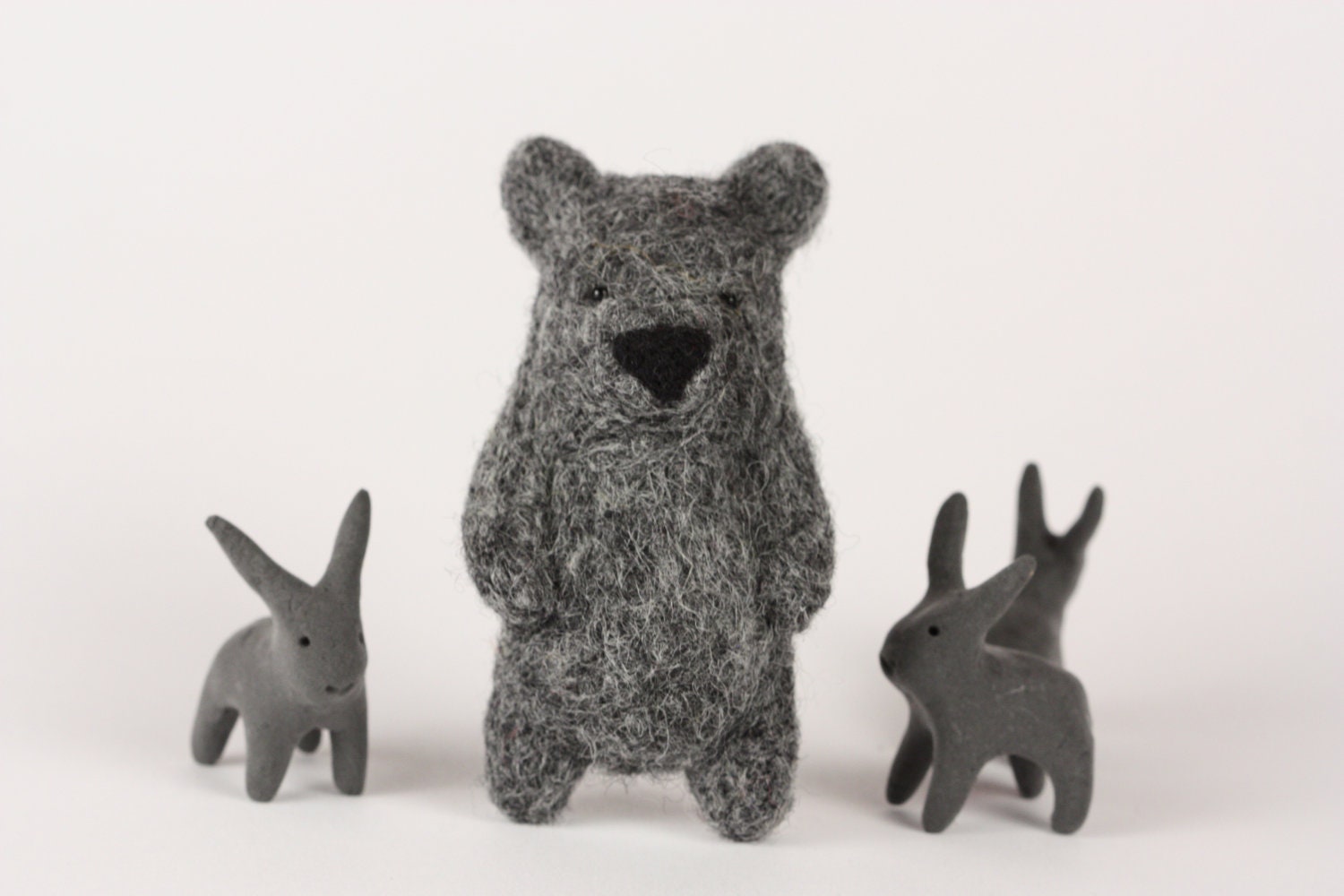 A dark grey felted bear brooch