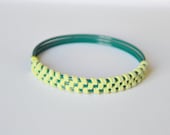 Suede bangle. Lime green suede in herringbone pattern woven together around three teal green enamel bangles. Med size.