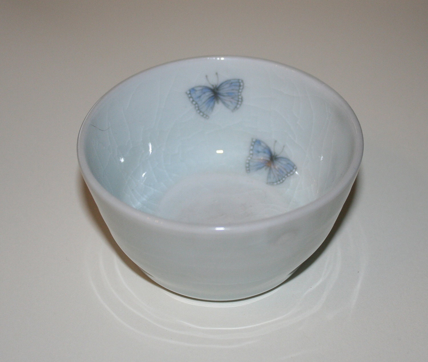 Porcelain ceramic, bowl in palest blue crackle glaze with pair of blue butterflies