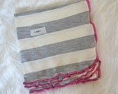 Baby girl swaddler. Soft stretchy knit material. Size 31 by 40 inches.   Colors- gray and cream with pink edging.   Made by lippy brand.