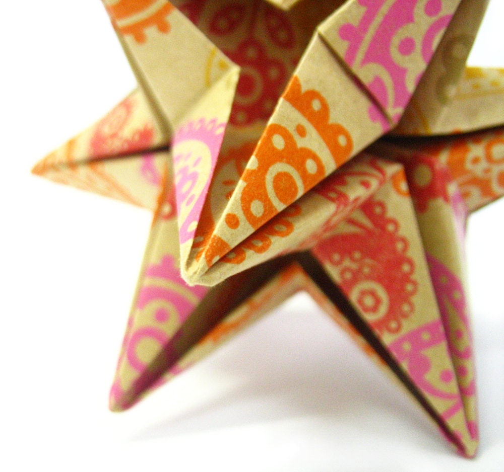Origami ornament, paper star handmade, pink, orange, red and gold paisley against a pale brown background