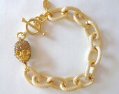 Textured gold link bracelet with gold pave skull charm
