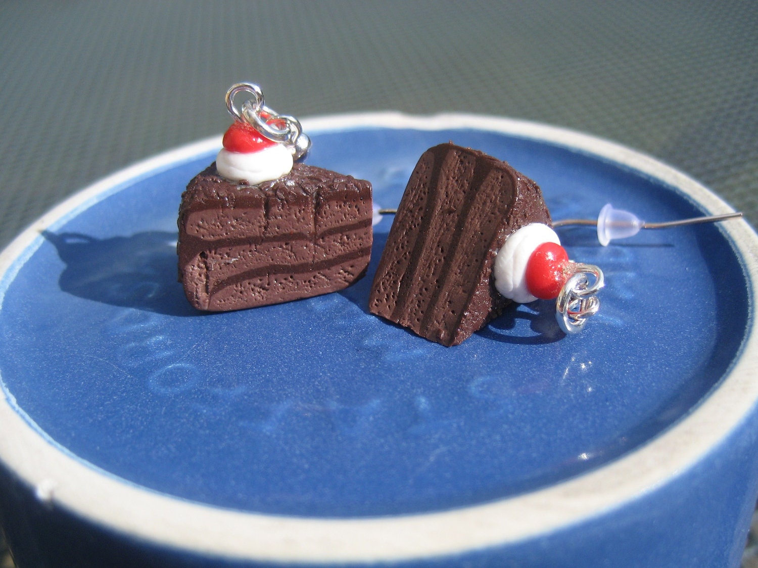 Chocolate frosted chocolate cake earrings with chocolate sprinkles, whipped cream, and a cherry: an homage to Portal made from polymer clay.