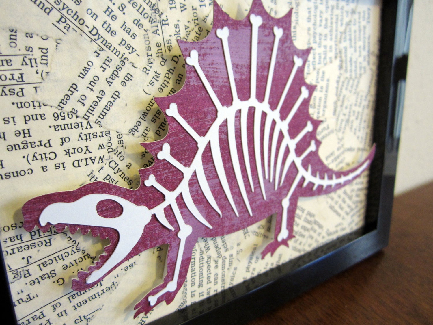 Dinobones - Dinosaur with Bones, Book Page Collage Background - Cut Paper Framed Wall Art - Purple, White with Black Frame