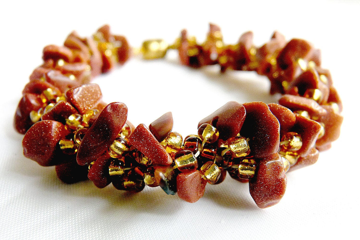 Woven spiral rope bracelet featuring goldstone chips and a magnetic clasp