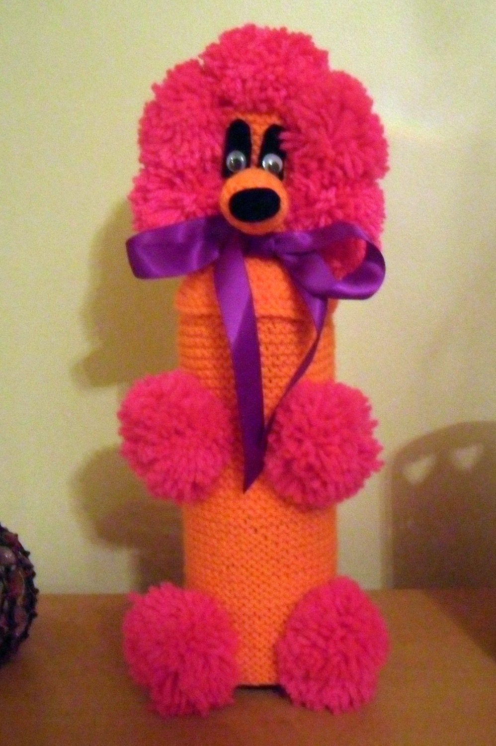 Brooke the bright orange and pink Gin Poodle with a purple ribbon bow collar