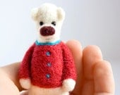 White bear with pinkish red sweater and a blue collar, brooch